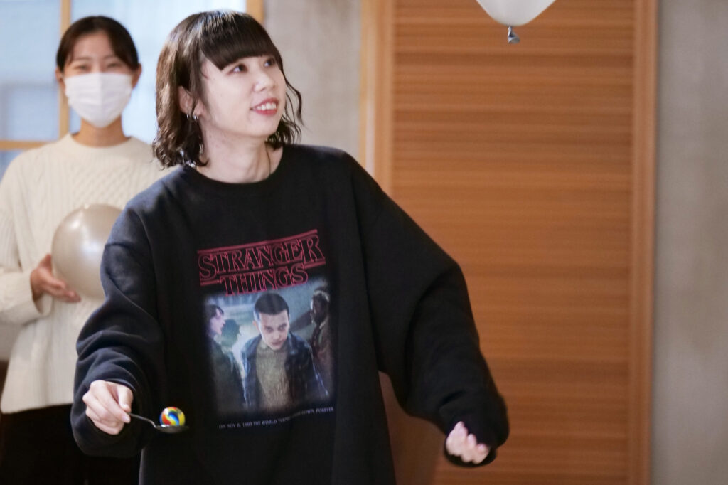 ピンポン玉を乗せたスプーンを片手に風船を見つめるメンバー